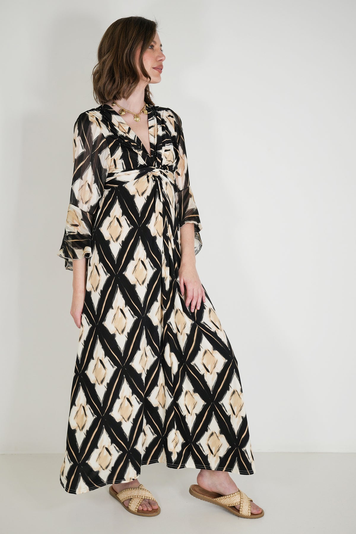 Woman wearing a long, patterned dress against a white background