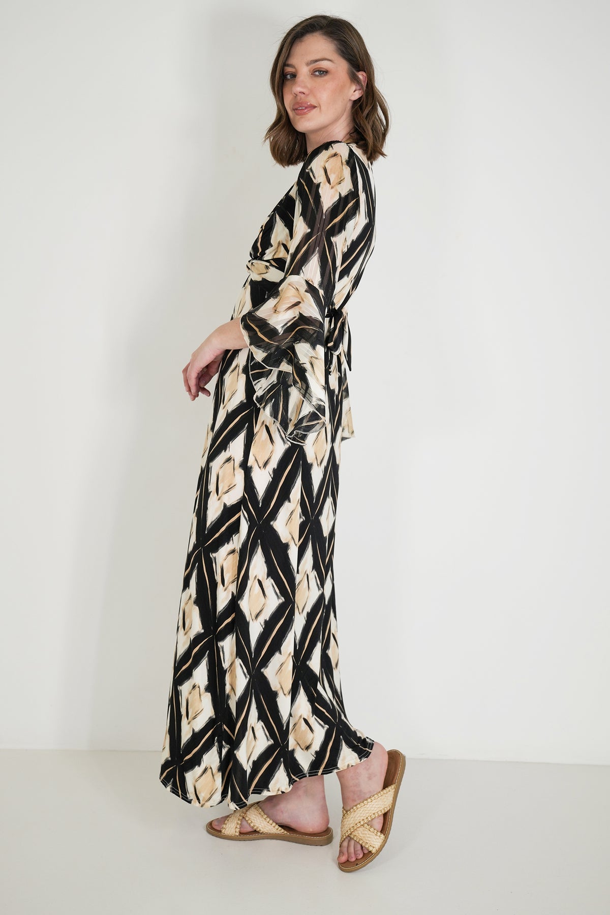 Woman wearing a long, patterned dress against a white background