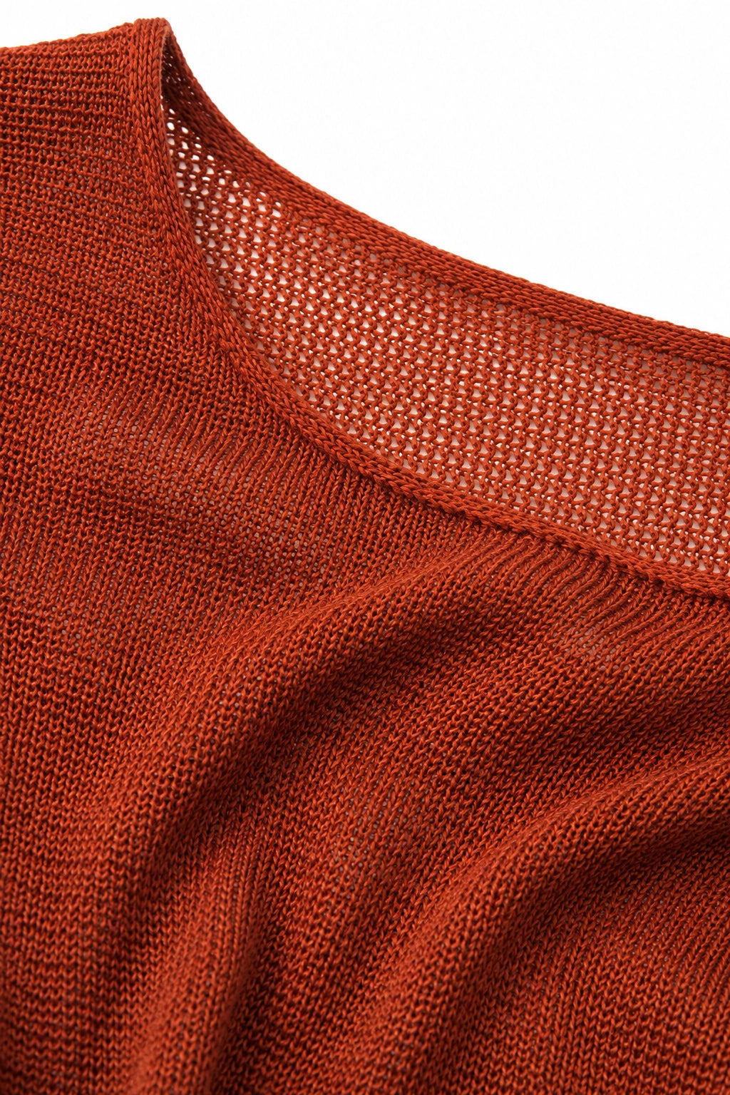 Close-up of a rust-orange knit sweater showing the textured fabric and a wide, open mesh neckline.