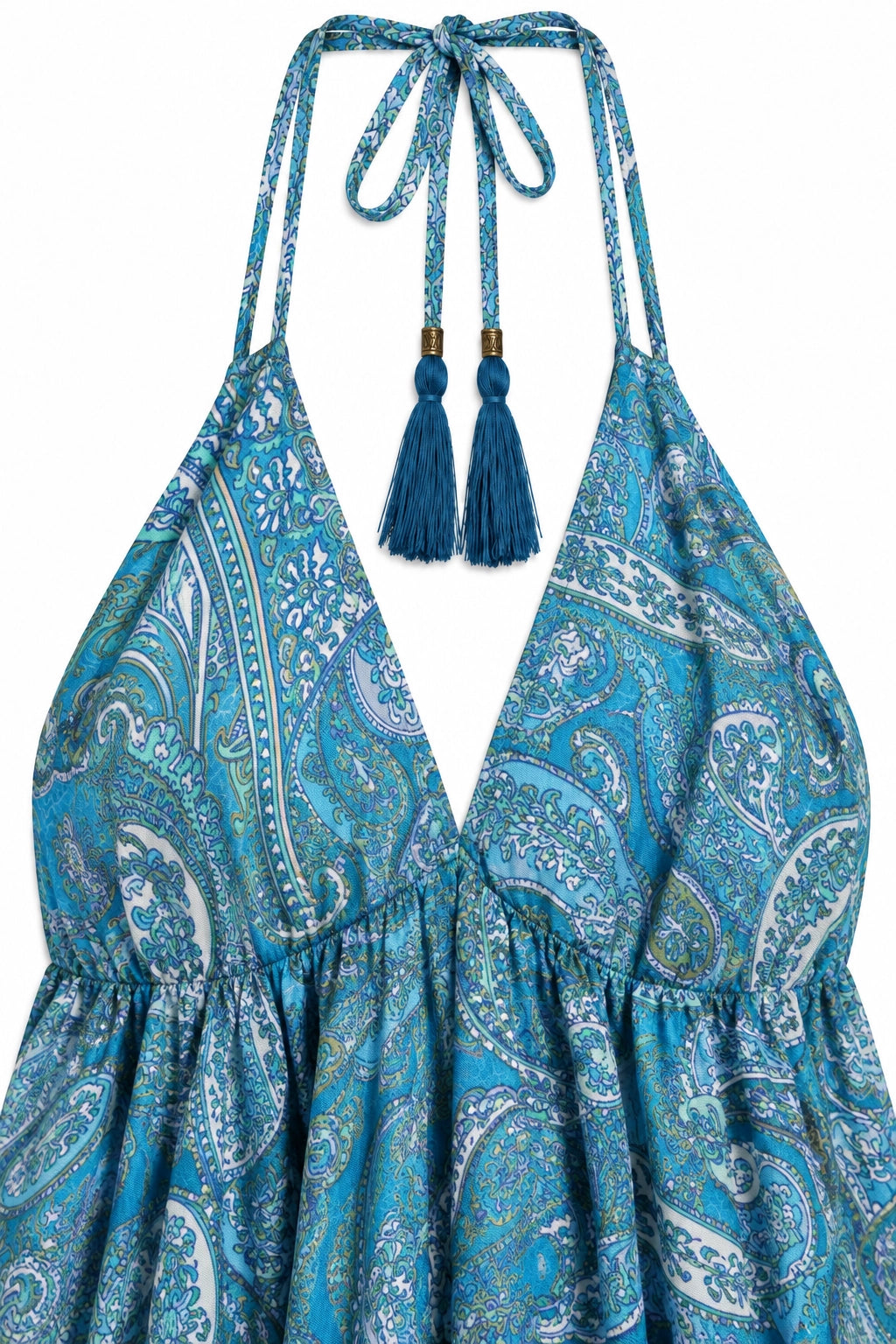 A close-up of a halter-neck dress with a blue and white paisley pattern, featuring tie straps with blue tassels at the neckline.