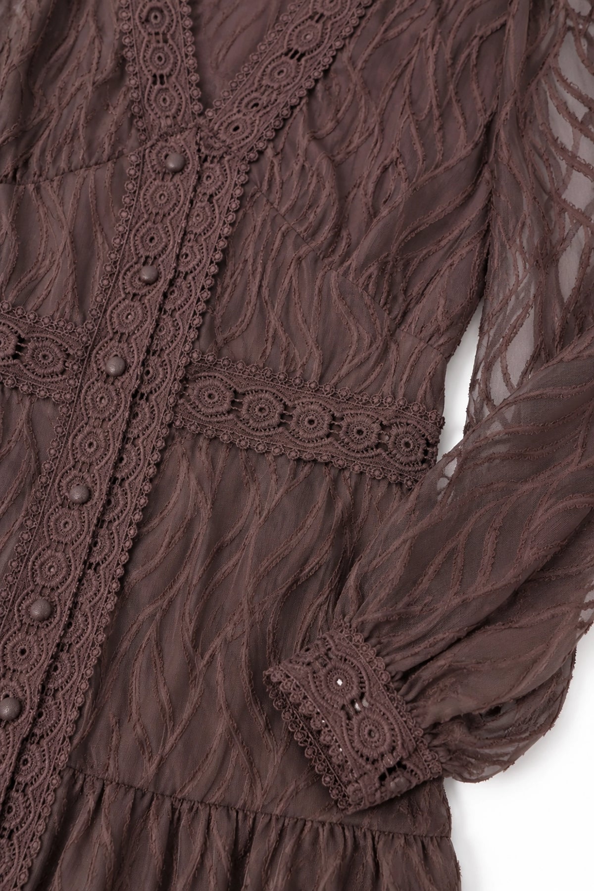Close-up of a brown lace dress with intricate details on a white background