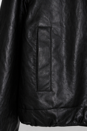Close-up of a black leather jacket with a pocket detail on a light gray background