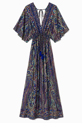 A bohemian-style maxi dress with a vibrant paisley pattern in shades of blue, purple, green, and gold, featuring a split neckline with tie details and a drawstring waist.