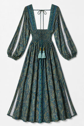 A long-sleeved bohemian-style maxi dress with a square neckline, tie-front detail, and tassel accents, featuring a blue and green paisley pattern on a light background.