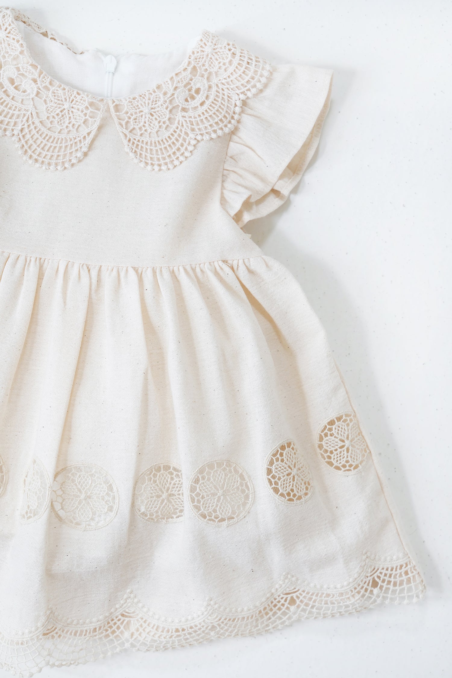 White dress with intricate lace detailing on a white background