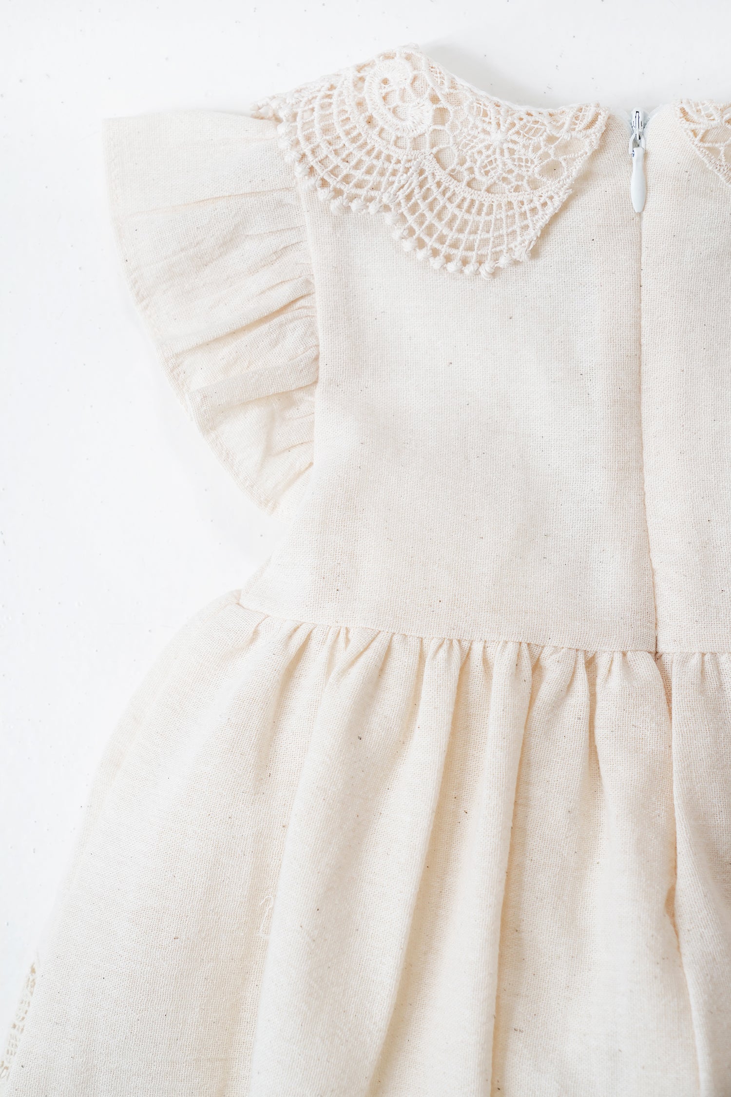 Cream-colored dress with crochet details on a white background