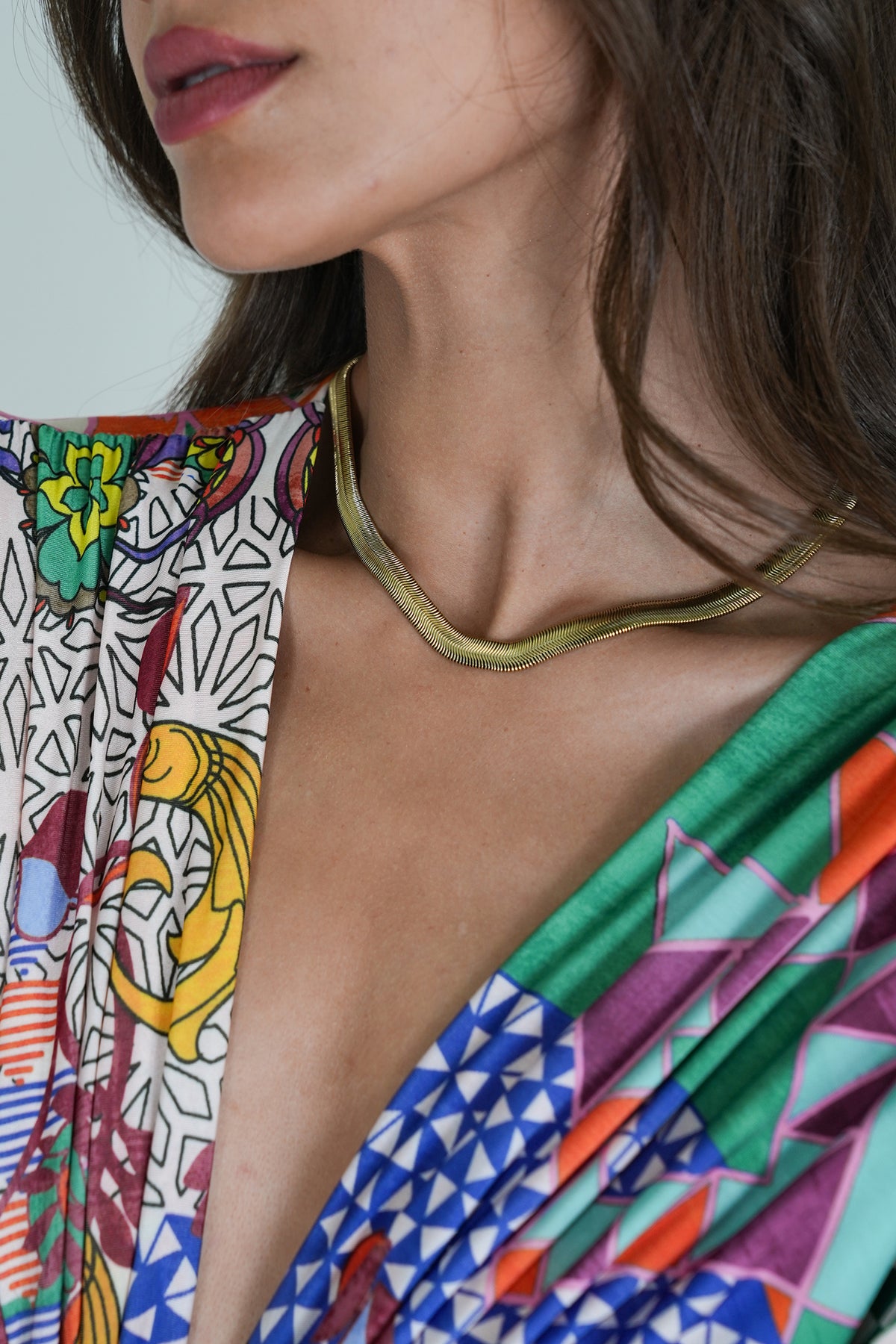 Close-up of a person wearing a colorful patterned garment with a green necklace.