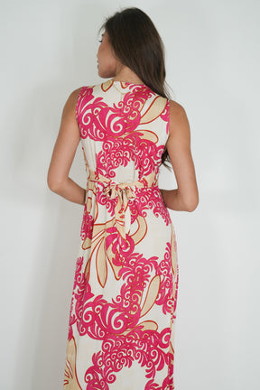 Woman wearing a sleeveless dress with pink and white floral pattern on a plain background