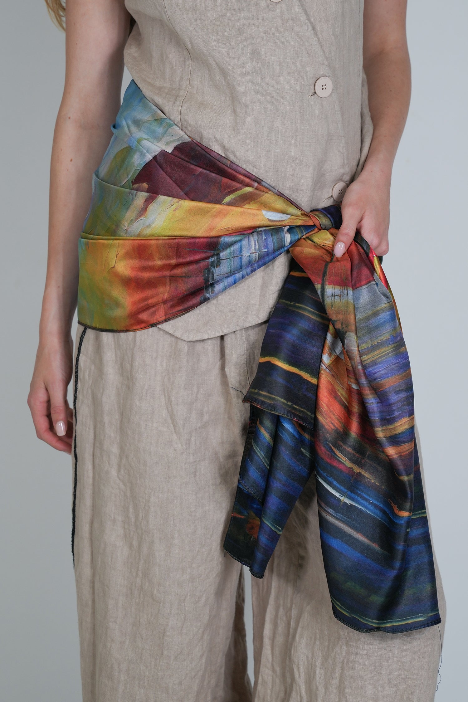 Person wearing a colourful tie-dye scarf with a plain background