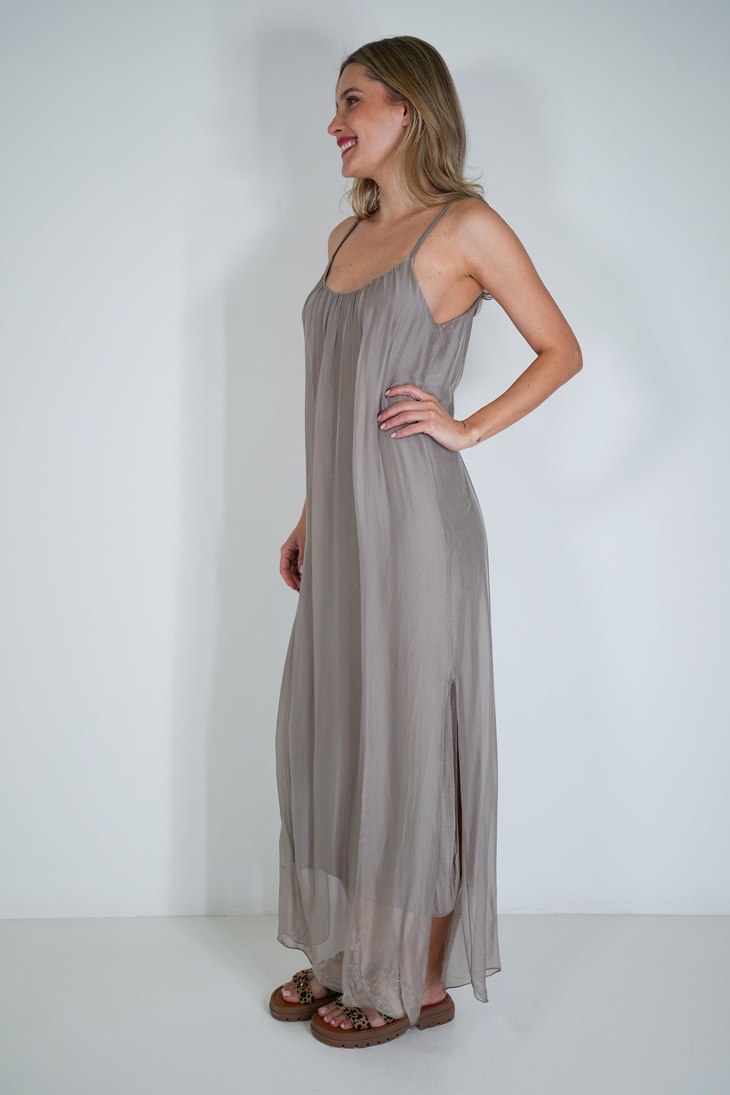 Woman wearing a long, light gray dress against a white background