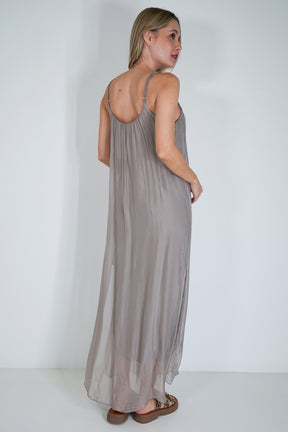 Woman wearing a long, light gray dress against a white background