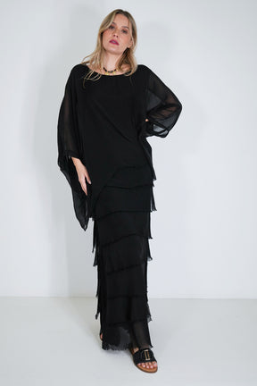 Woman wearing a black layered dress against a white background