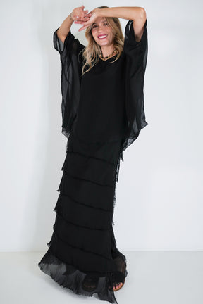 Woman wearing a black dress with ruffled layers on a white background
