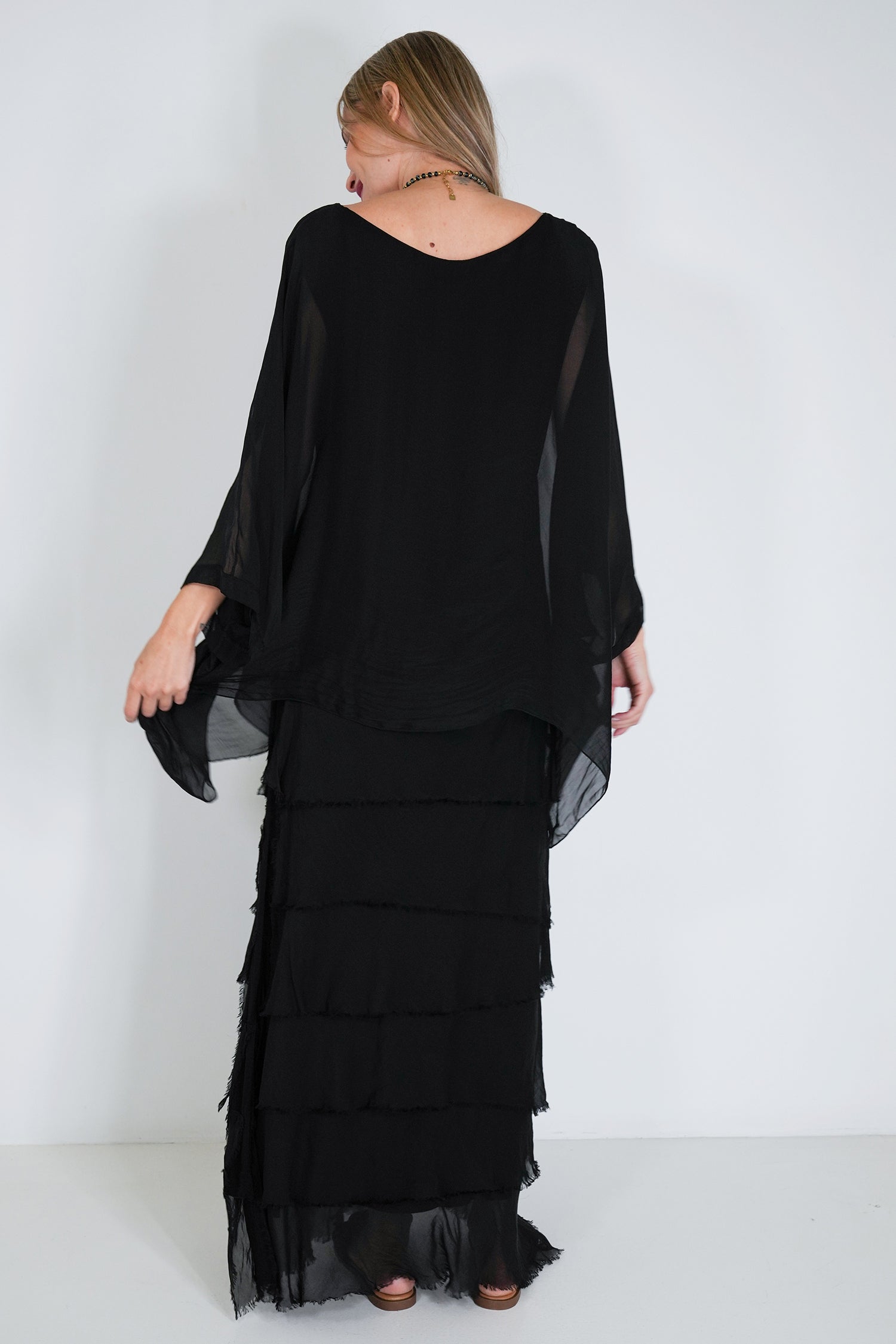 Woman wearing a black, layered dress against a white background