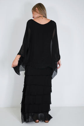 Woman wearing a black, layered dress against a white background