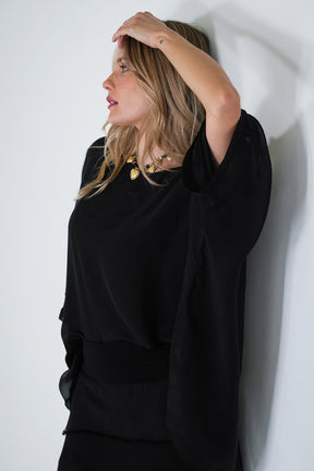 Woman wearing a black outfit against a white wall