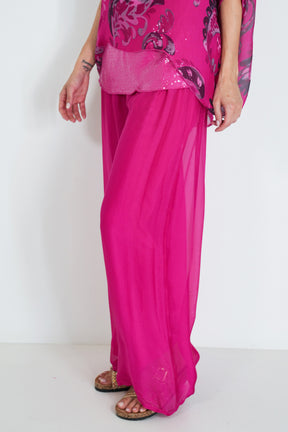Person wearing a bright pink outfit with a floral top on a white background