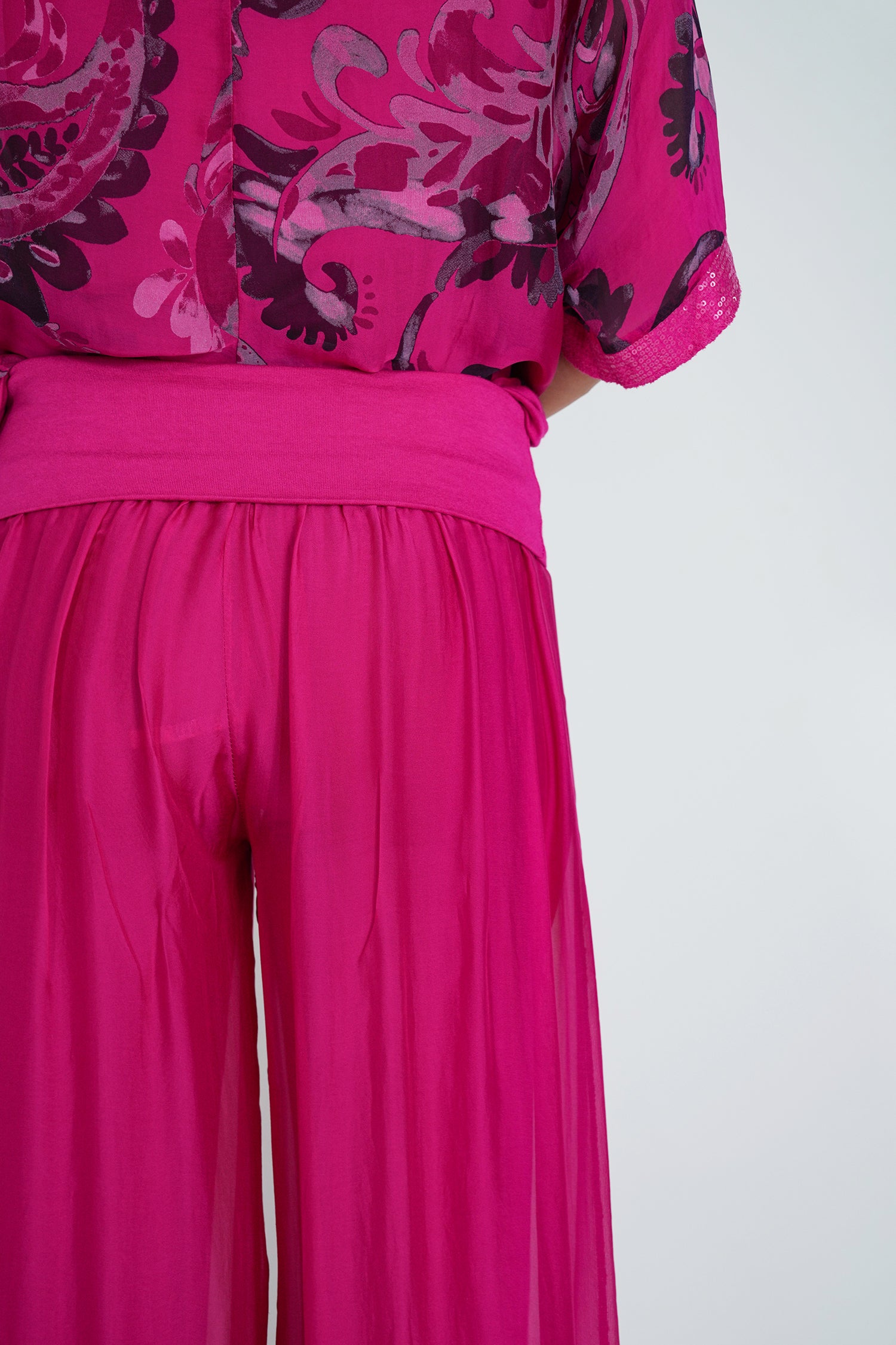 Bright pink outfit with floral patterned top on a white background