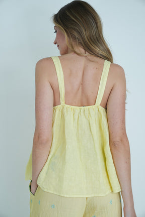 Woman wearing a yellow sleeveless top against a plain background