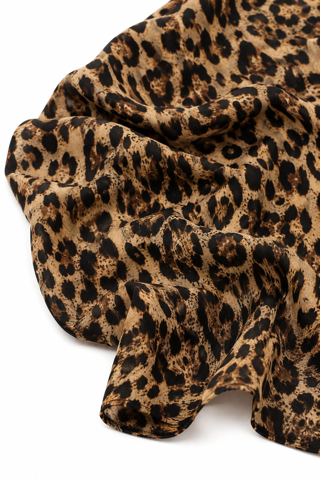 A close-up of draped leopard print fabric with a tan base and black spots, shown against a plain white background.
