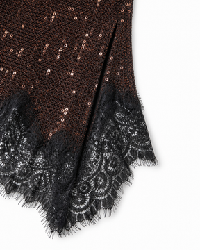 Close-up of a brown and black patterned fabric with sequins and lace trim on a white background