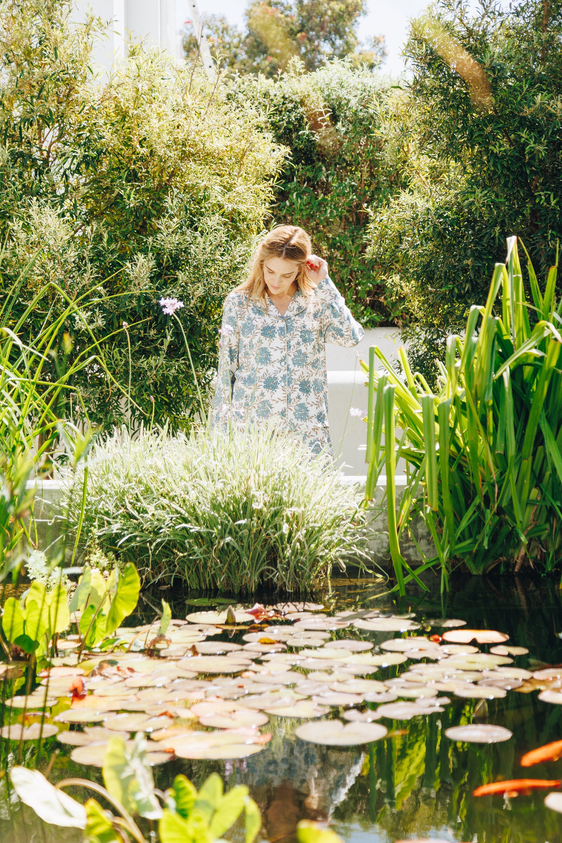 Woman standing by a pond with lily pads and greenery