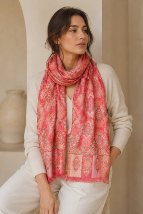 Woman wearing a pink patterned scarf in a neutral setting