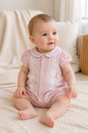 Baby in a pink outfit sitting on a soft surface